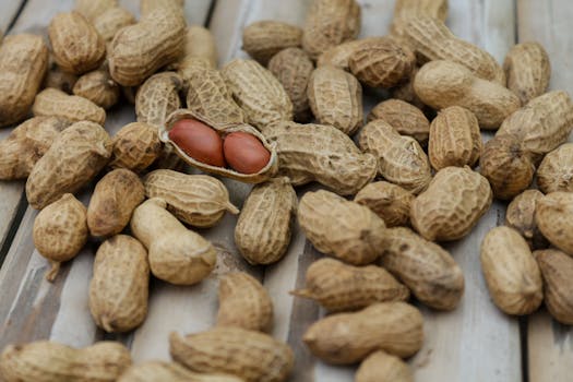 A detailed close-up of peanuts in their shells scattered on a wooden surface.